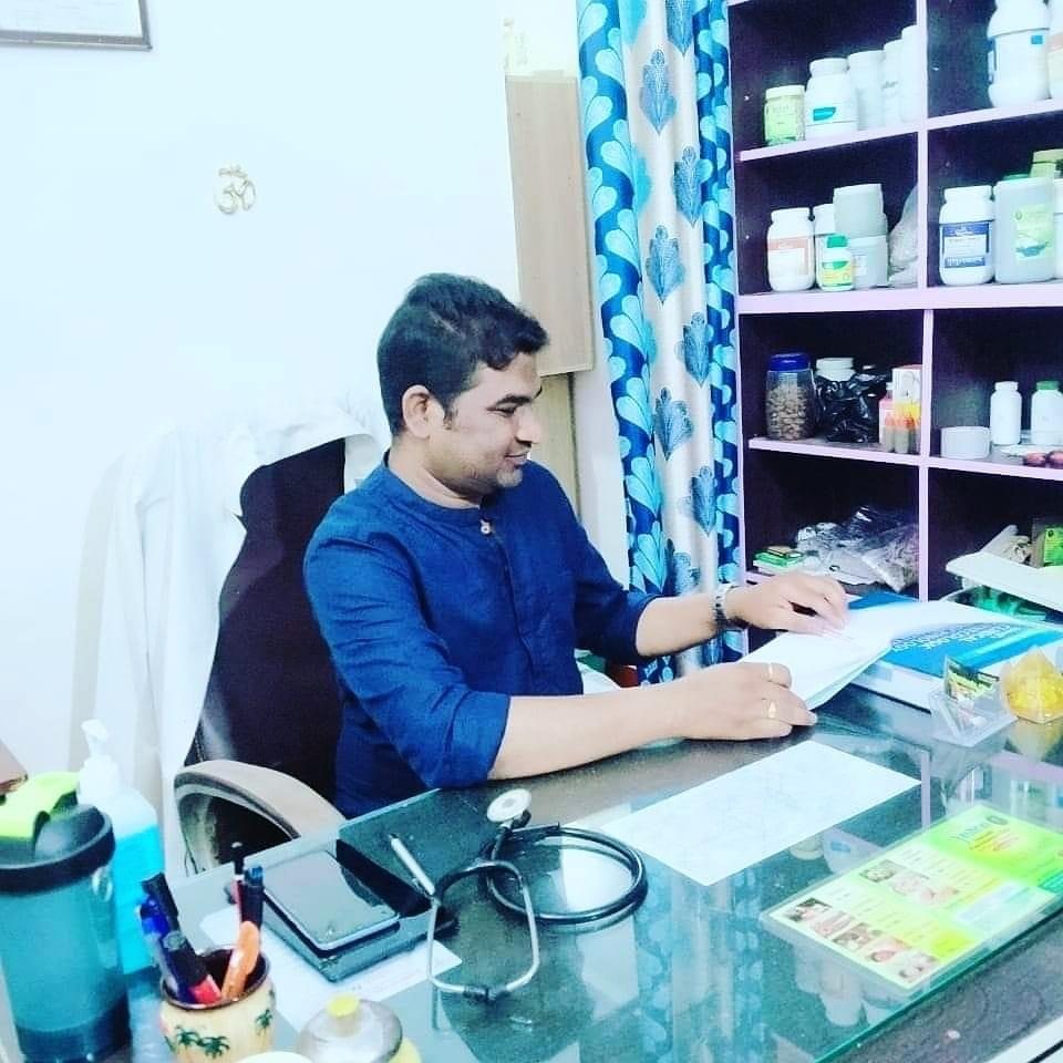 An Ayurvedic doctor reviewing notes and writing a care plan during a clinic consultation